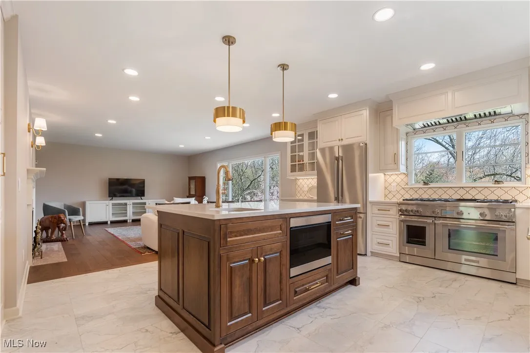 Kitchen featuring a sink, marble finish floor, stainless steel appliances, light countertops, and recessed lighting