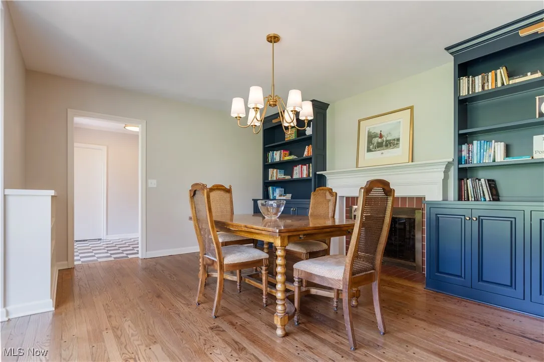 Dining room featuring baseboards, wood finished floors, built in shelves, and an inviting chandelier
