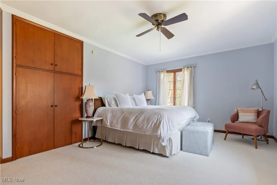 Bedroom with baseboards, light colored carpet, and ornamental molding