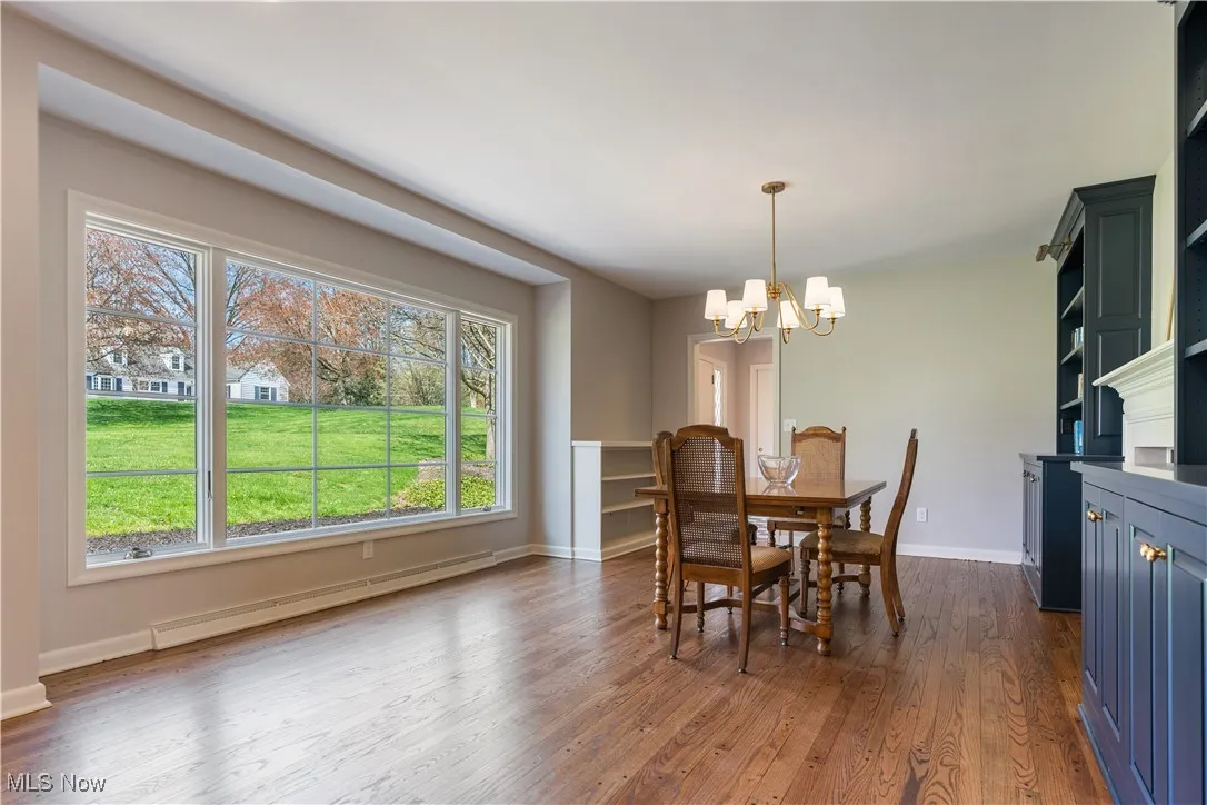 Dining space with a baseboard heating unit, an inviting chandelier, dark wood-style floors, and baseboards