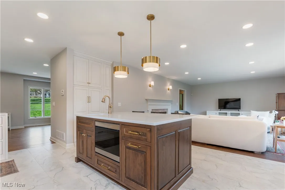 Kitchen featuring a sink, built in microwave, marble finish floor, light countertops, and recessed lighting