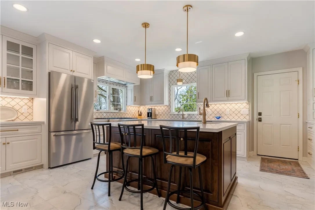 Kitchen featuring tasteful backsplash, a kitchen breakfast bar, freestanding refrigerator, light countertops, and recessed lighting