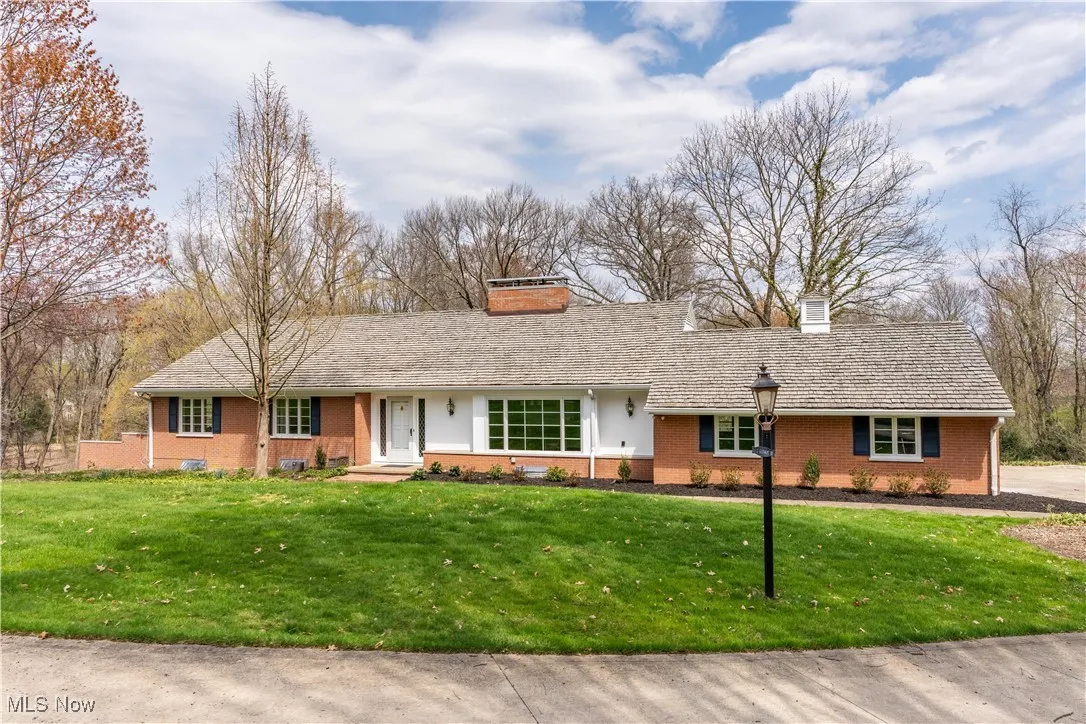 Ranch-style house with a chimney, brick siding, and a front yard