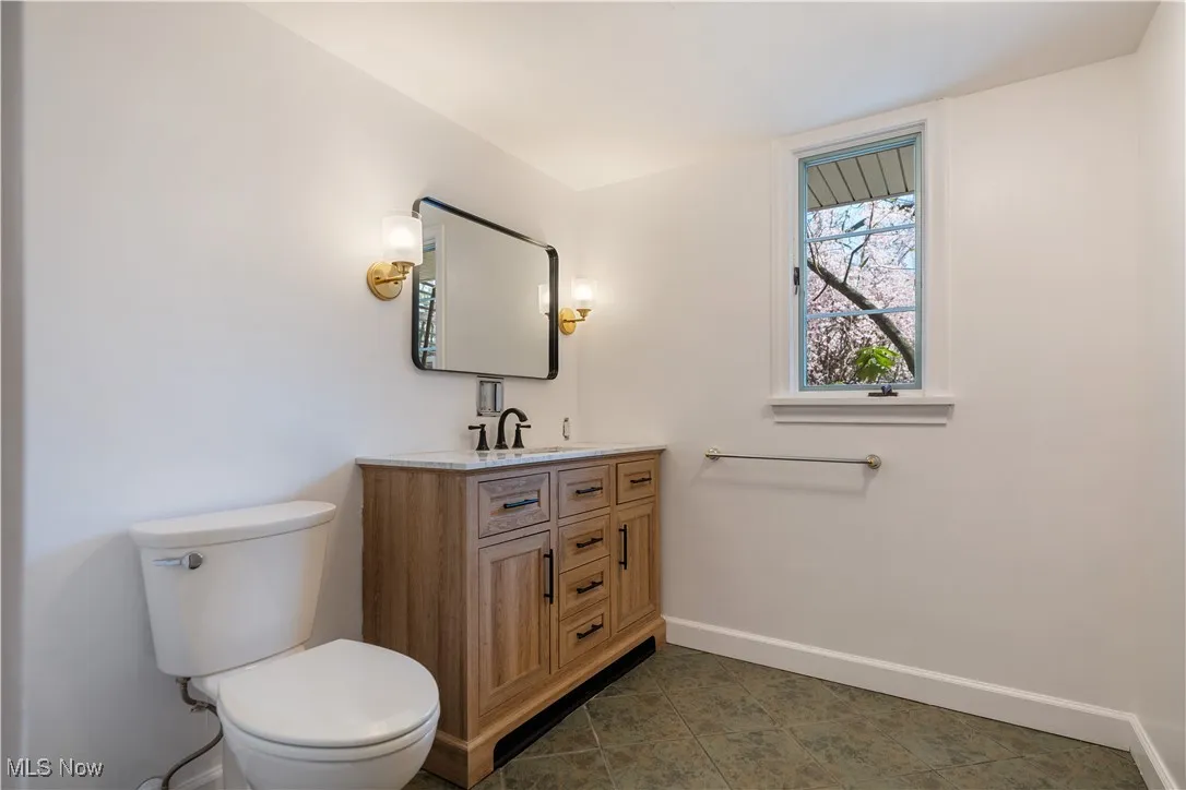 Bathroom with tile patterned floors, baseboards, vanity, and toilet