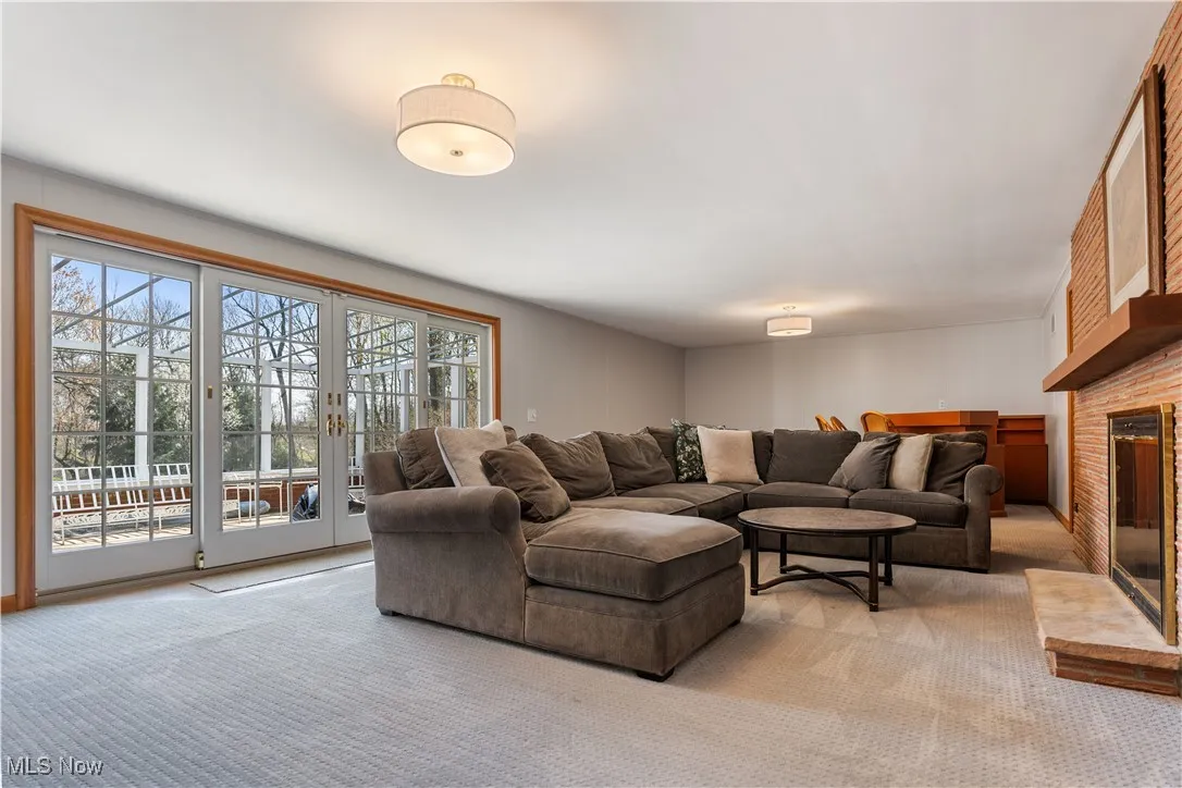 Carpeted living room featuring a wealth of natural light, a brick fireplace, and french doors