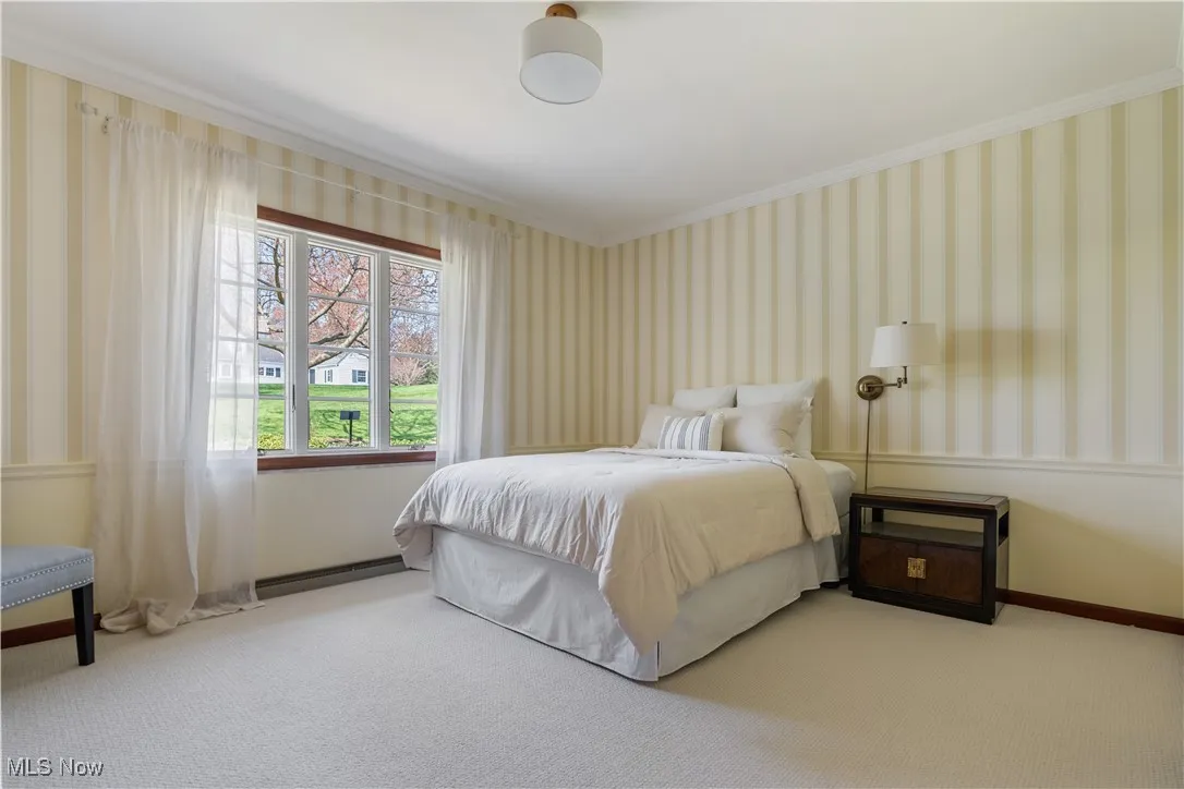 Bedroom with baseboards, ornamental molding, wallpapered walls, and carpet