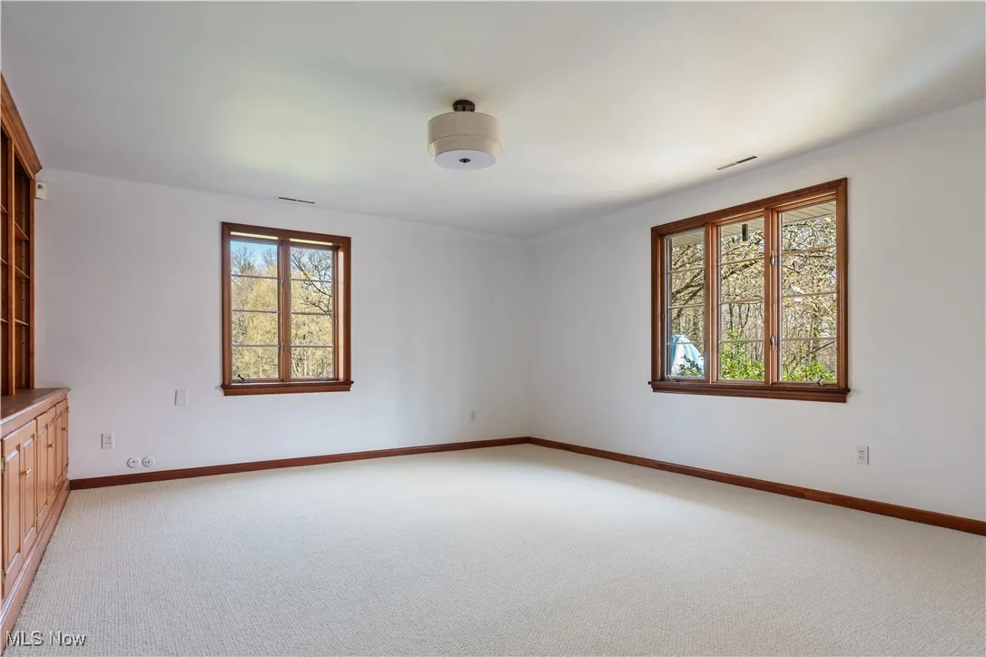 Empty room featuring light colored carpet, baseboards, crown molding, and visible vents