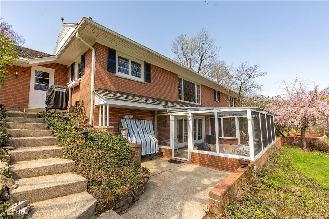 Rear view of house with a sunroom, brick siding, and a patio