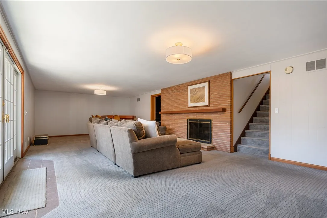 Living area featuring light carpet, stairs, visible vents, and baseboards