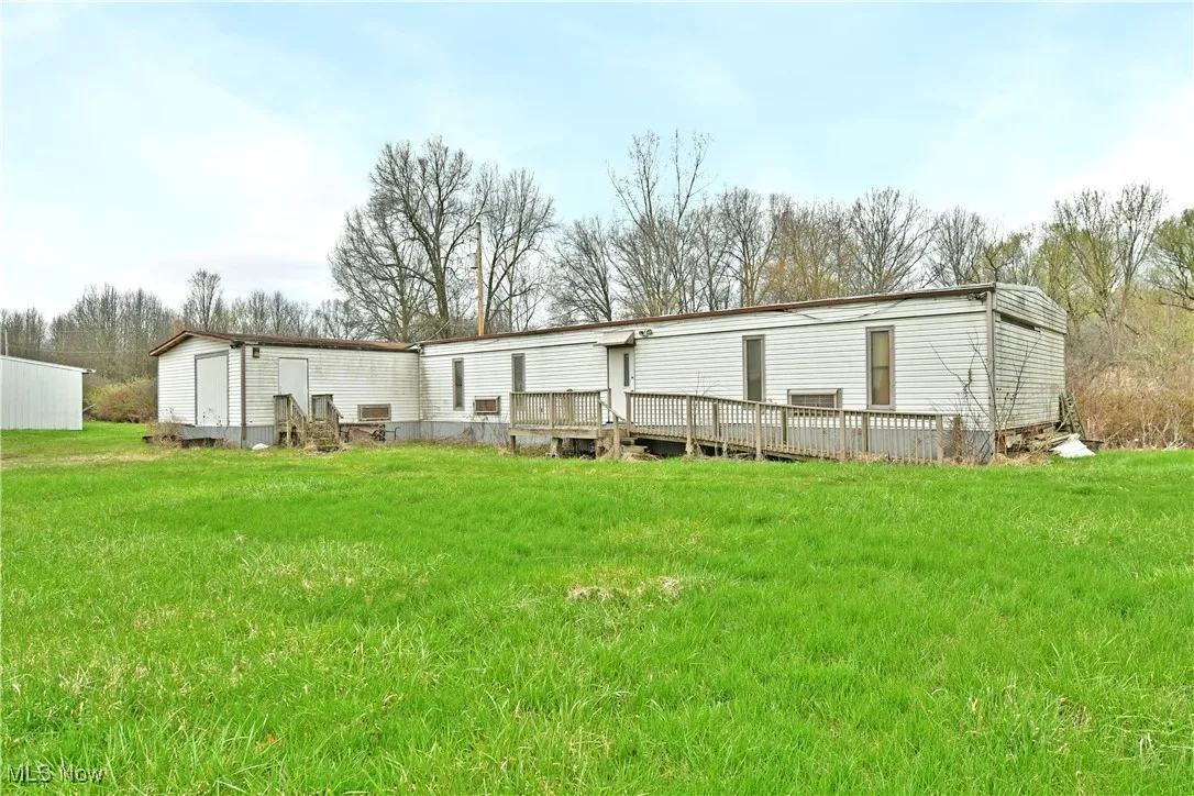 Rear view of house featuring a wooden deck and a yard