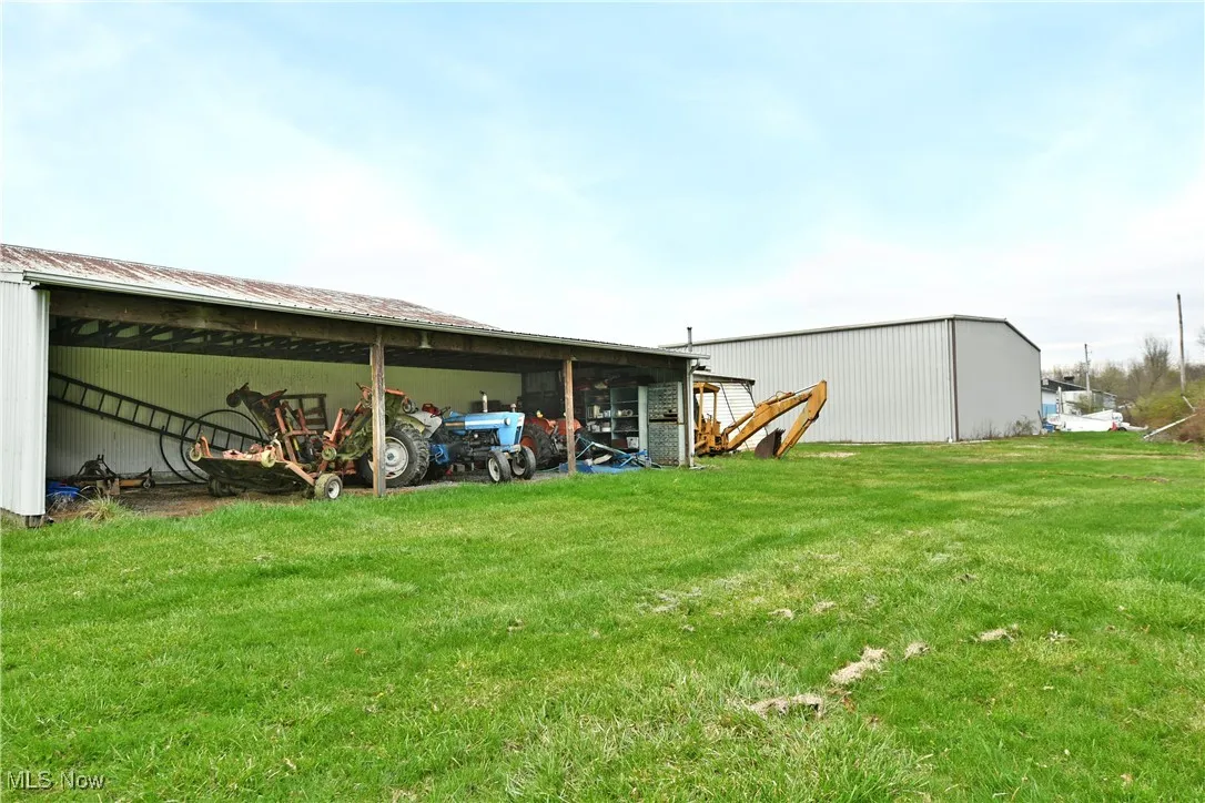 Back of property with a pole building, a lawn, and an outbuilding
