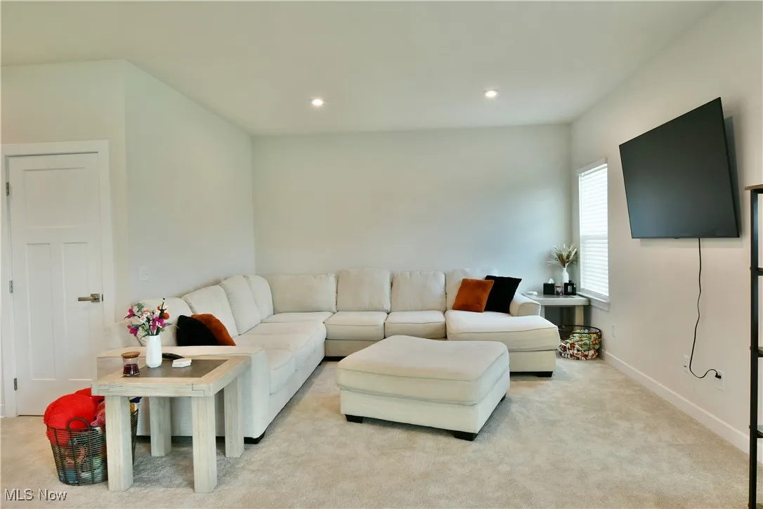 Living room featuring light carpet, baseboards, and recessed lighting
