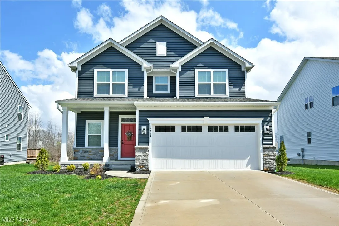 Craftsman style house with a front lawn, driveway, a porch, stone siding, and a garage