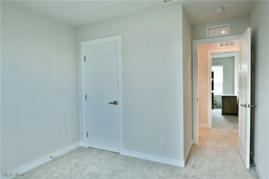 Unfurnished third  bedroom with baseboards, visible vents, and light colored carpet