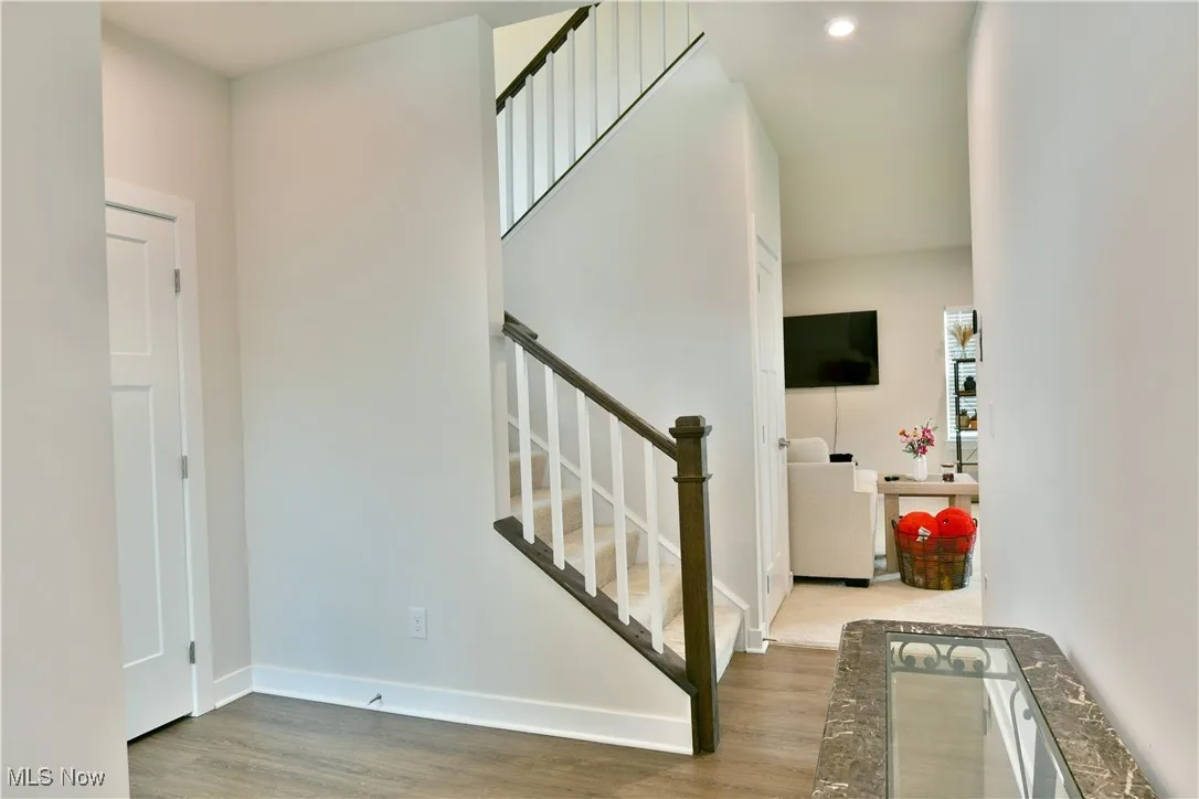 Stairs with baseboards, wood finished floors, and recessed lighting