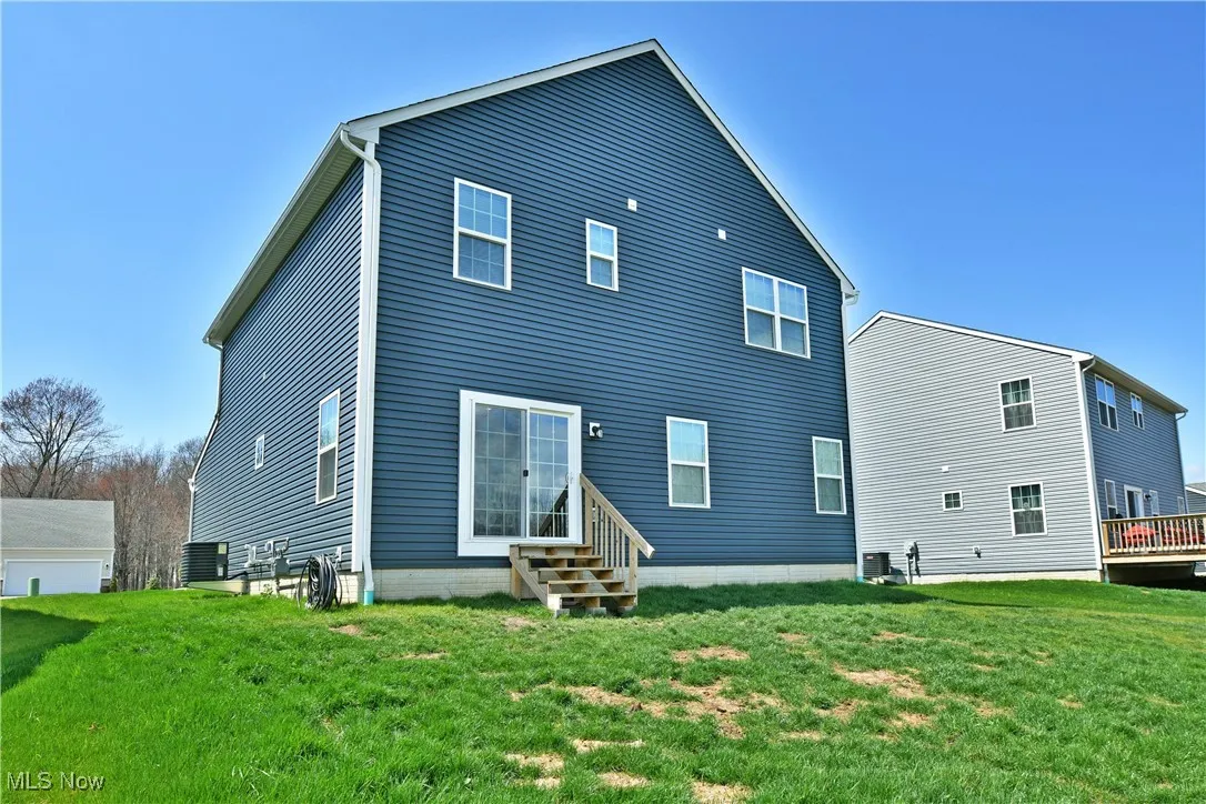 Rear view of house with a lawn and entry steps