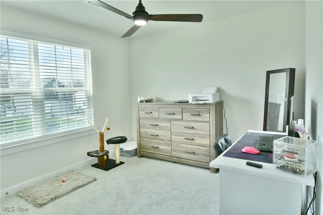Fourth bedroom with carpet and ceiling fan.