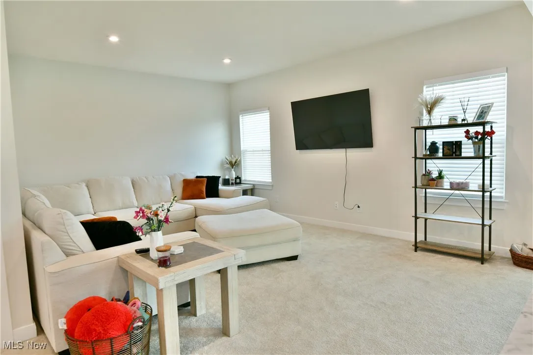 Living area featuring light carpet, baseboards, and recessed lighting