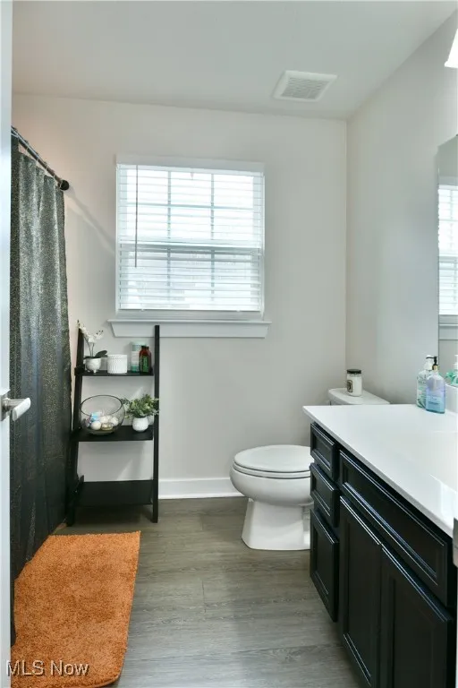 Second Bathroom with wood finished floors, vanity, baseboards, toilet, and visible vents