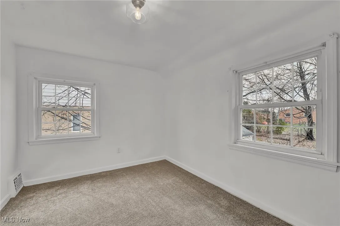 Carpeted empty room with baseboards and visible vents