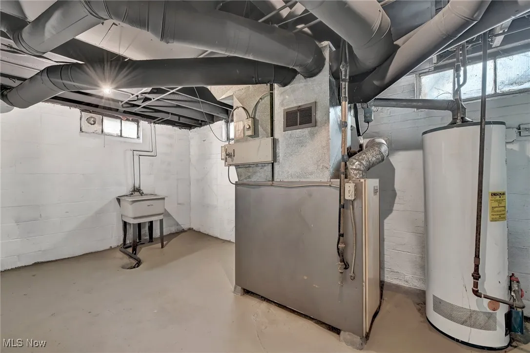 Basement with water heater, visible vents, and heating unit