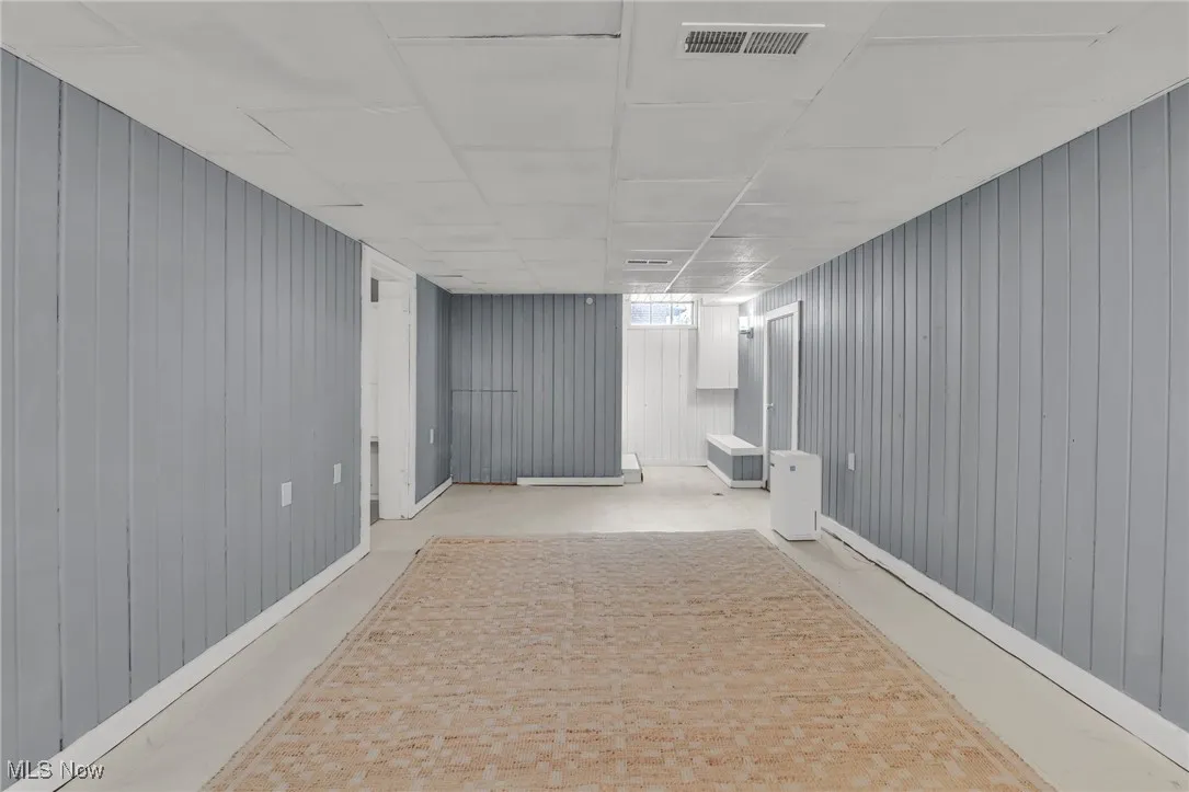 Below grade area featuring visible vents, baseboards, and wood walls