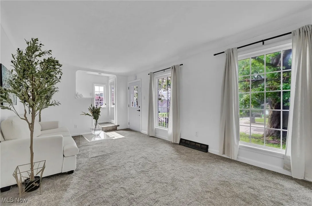 Unfurnished living room featuring carpet and baseboards