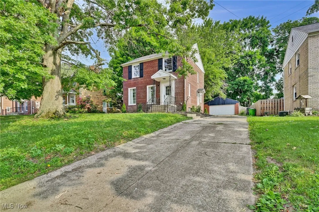 Colonial inspired home featuring an outbuilding, brick siding, and a detached garage