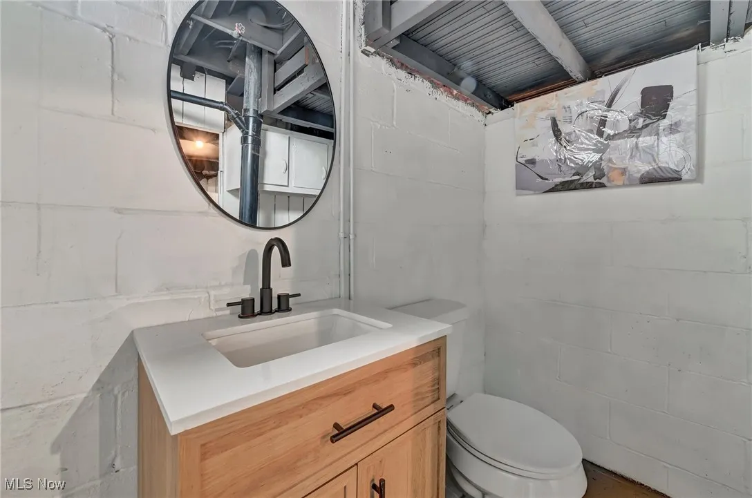 Half bathroom with concrete block wall, vanity, and toilet