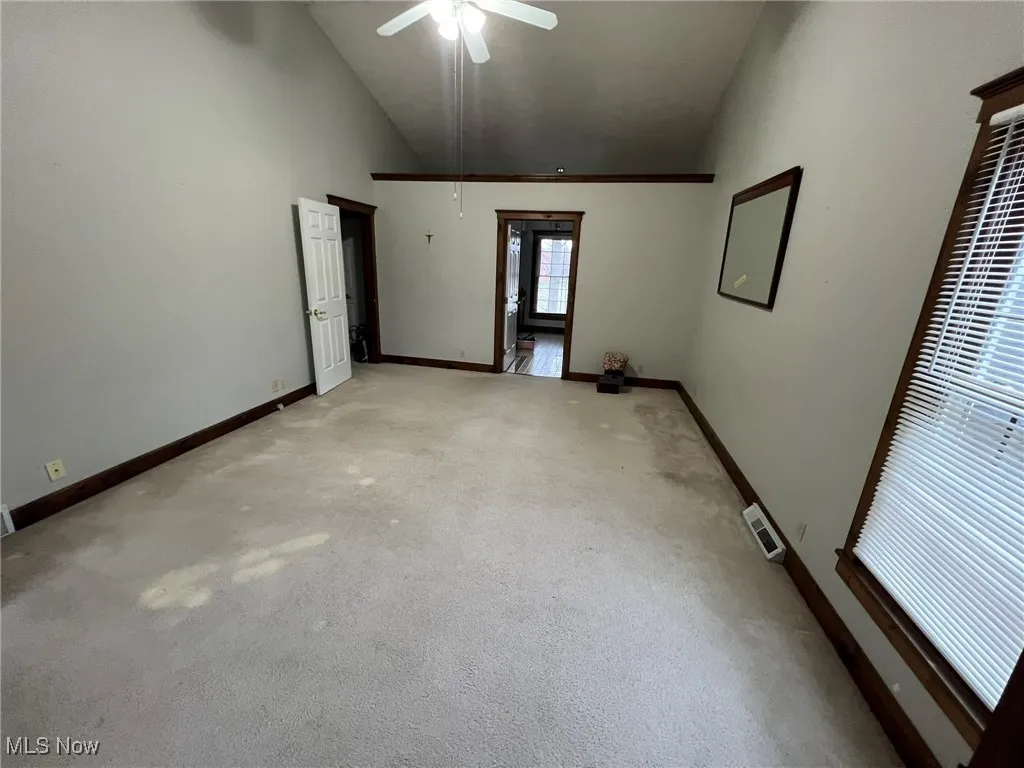 Unfurnished room with baseboards, visible vents, high vaulted ceiling, and ceiling fan