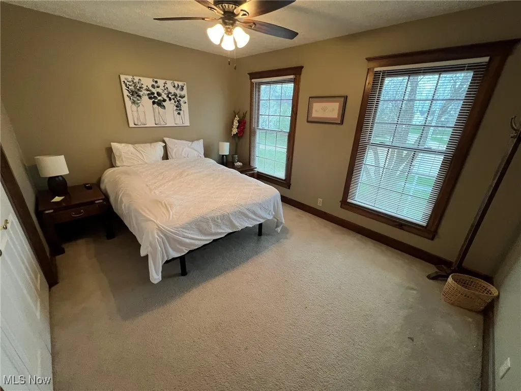 Bedroom with light carpet, a ceiling fan, and baseboards