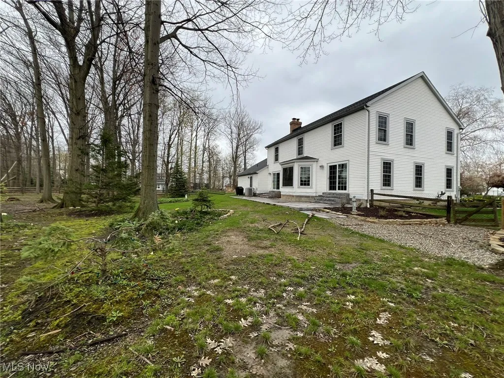 View of side of property with fence, a patio area, a chimney, and entry steps