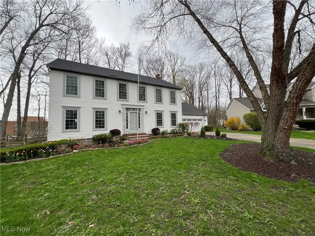 Colonial house with a garage, a front lawn, a chimney, and concrete driveway