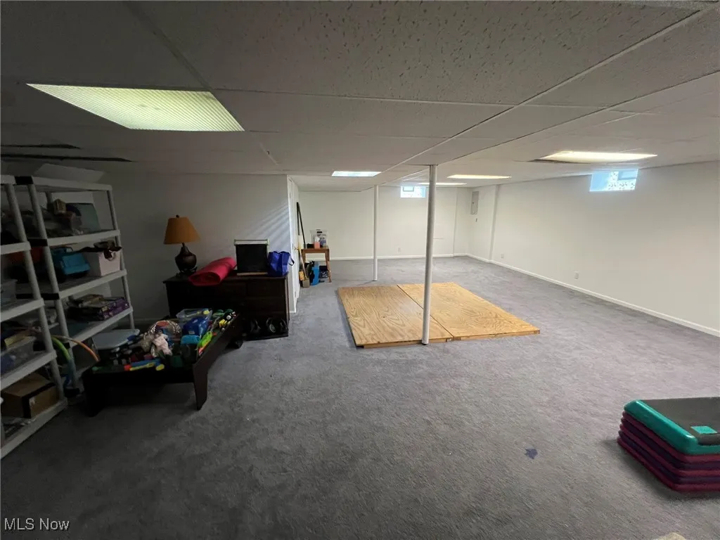 Basement with a paneled ceiling and carpet floors
