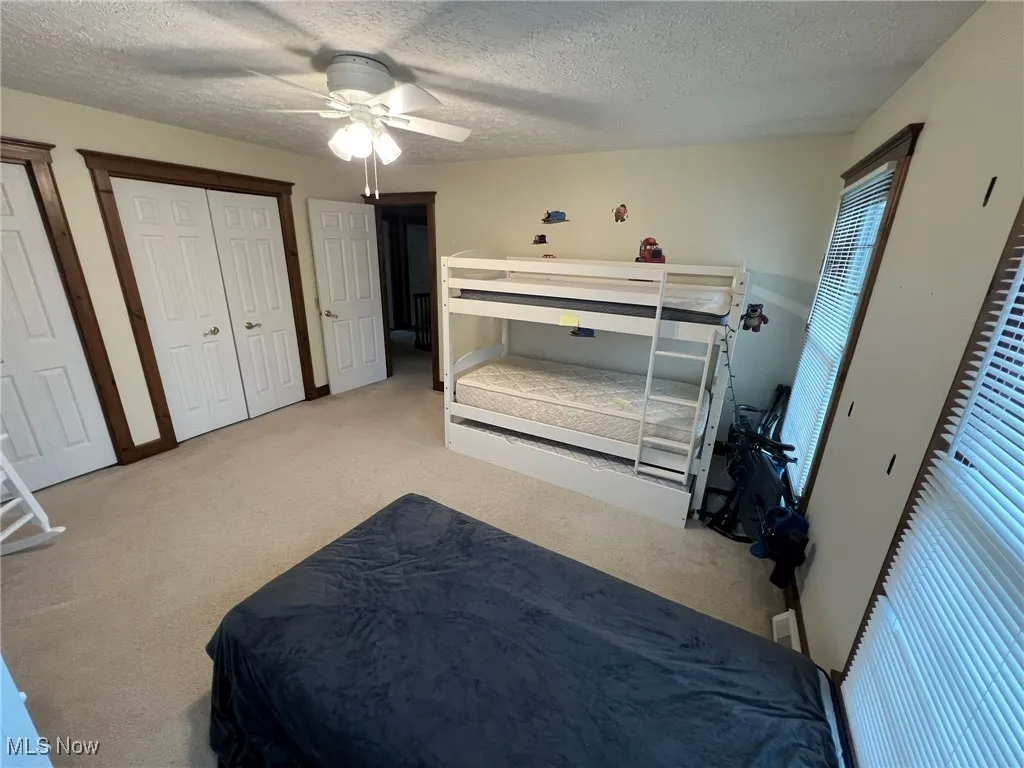 Carpeted bedroom with a textured ceiling and ceiling fan