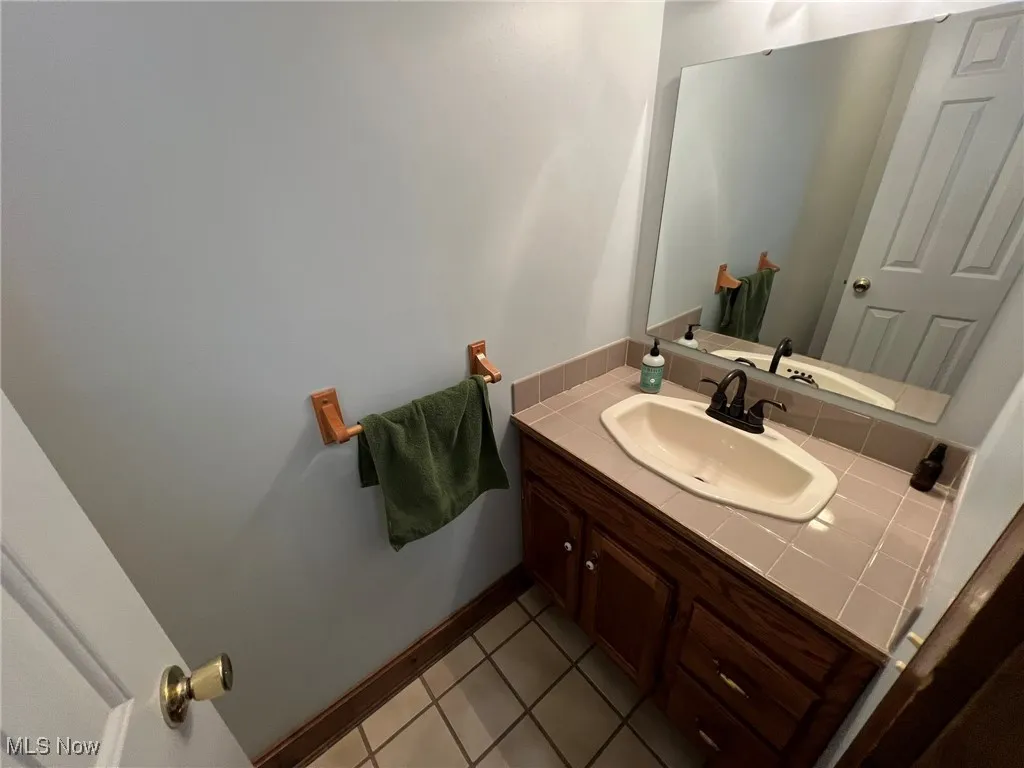 Bathroom with tile patterned floors, baseboards, and vanity