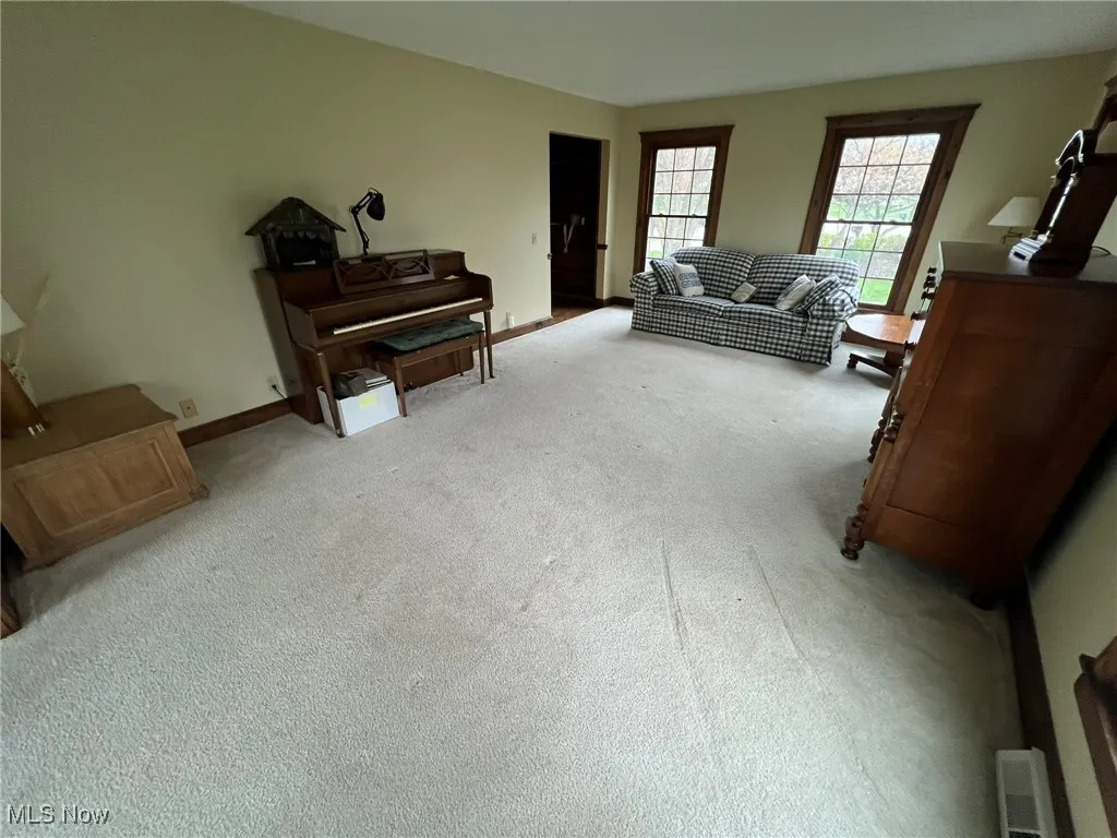 Living area with baseboards and light colored carpet