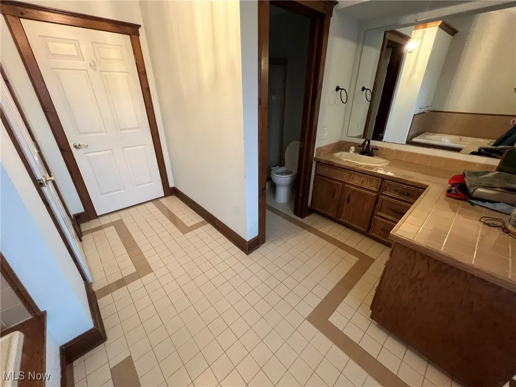 Bathroom with baseboards, tile patterned flooring, vanity, and toilet