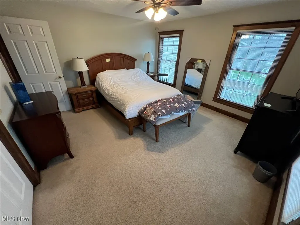 Bedroom featuring ceiling fan, baseboards, and light colored carpet