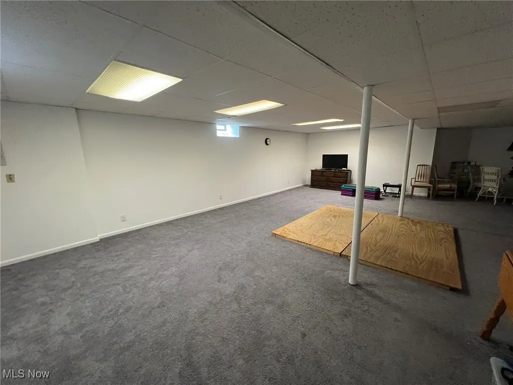 Basement featuring baseboards, carpet flooring, and a paneled ceiling