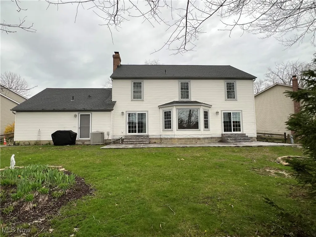 Rear view of property with a chimney, a patio, entry steps, and a lawn