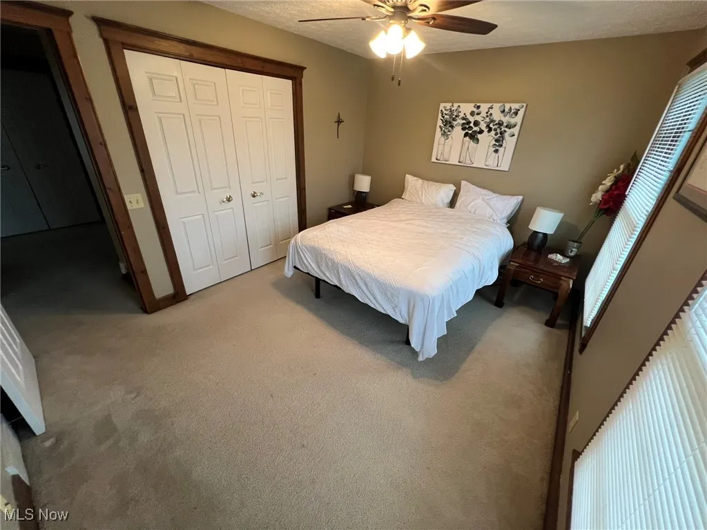 Bedroom featuring a closet, a ceiling fan, and light carpet