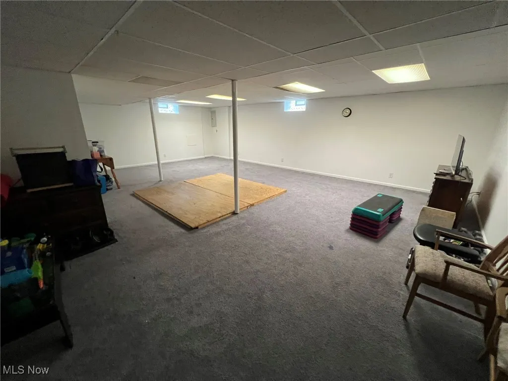 Below grade area featuring carpet floors, a paneled ceiling, and baseboards