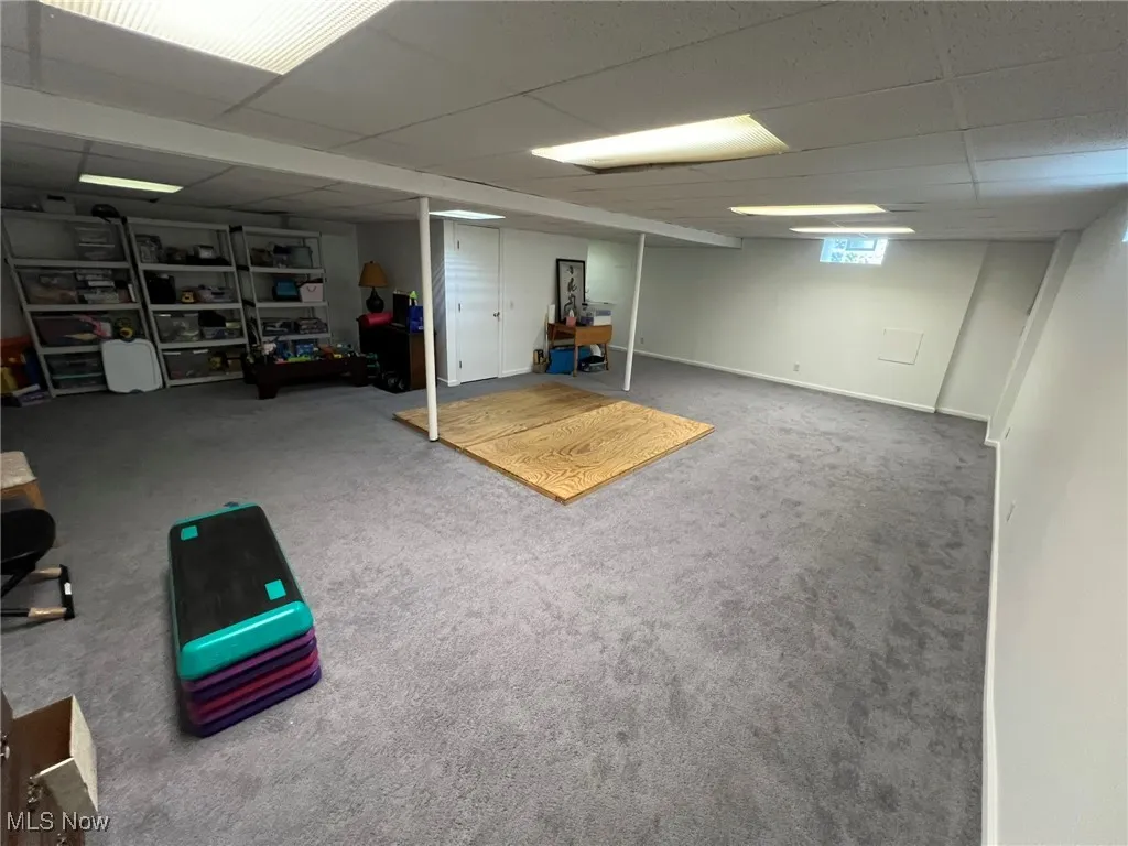 Below grade area featuring a paneled ceiling, baseboards, and carpet
