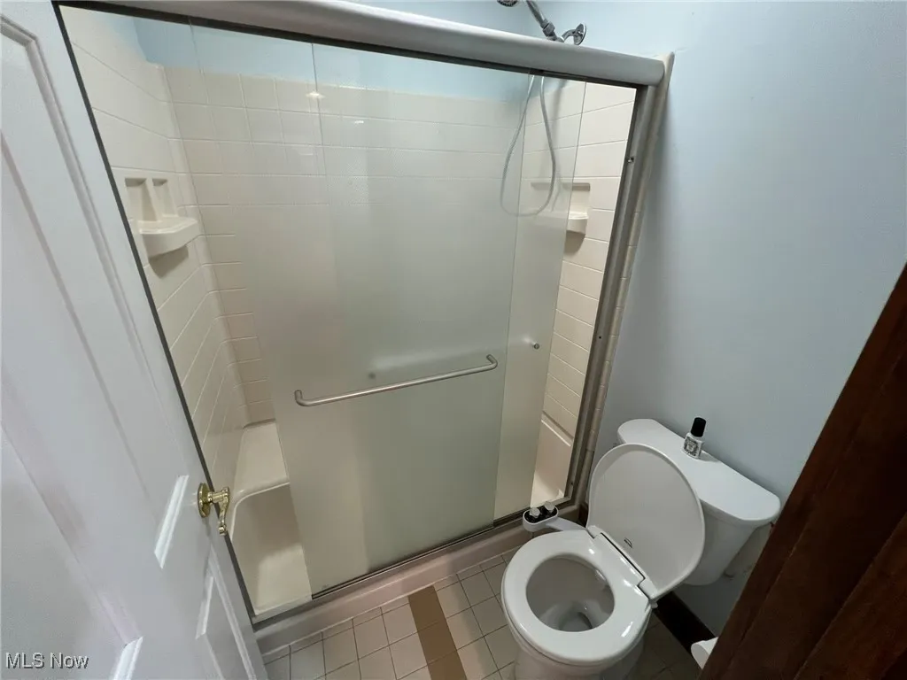 Full bathroom with tile patterned flooring, a shower stall, and toilet
