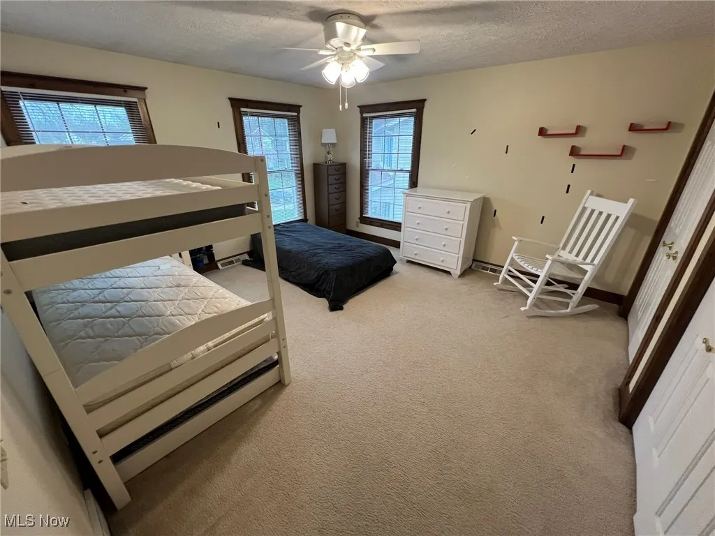 Bedroom featuring light colored carpet, a ceiling fan, and a textured ceiling