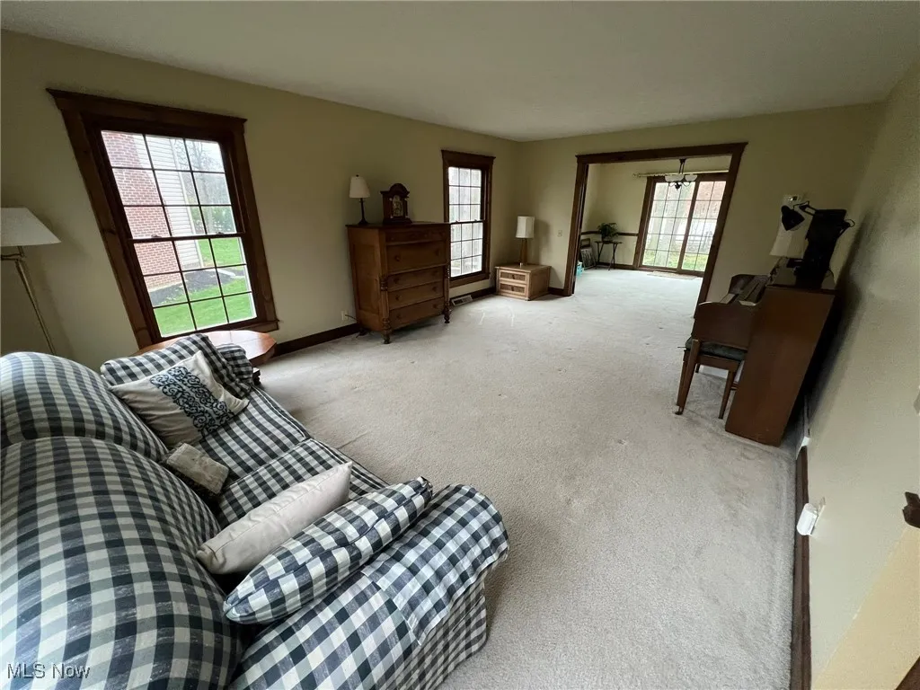 Carpeted living area with baseboards and an inviting chandelier
