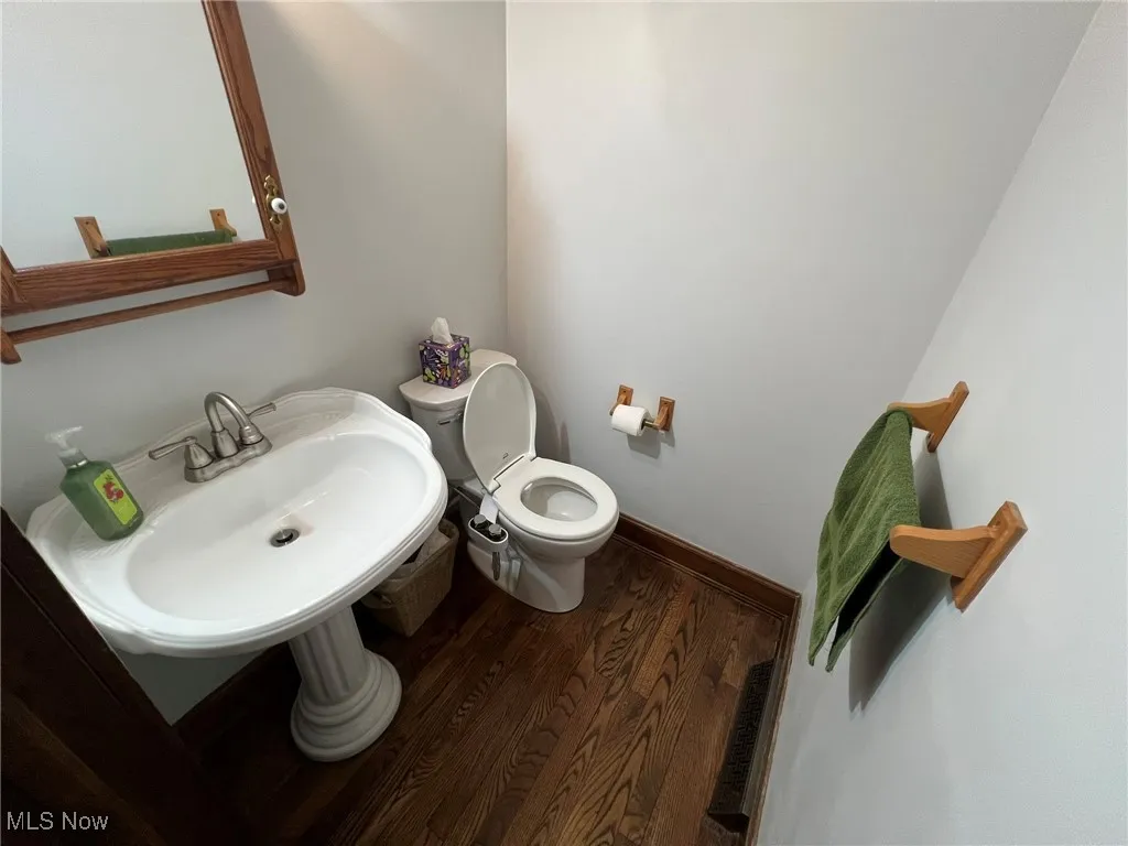 Bathroom with toilet, wood finished floors, visible vents, and a sink
