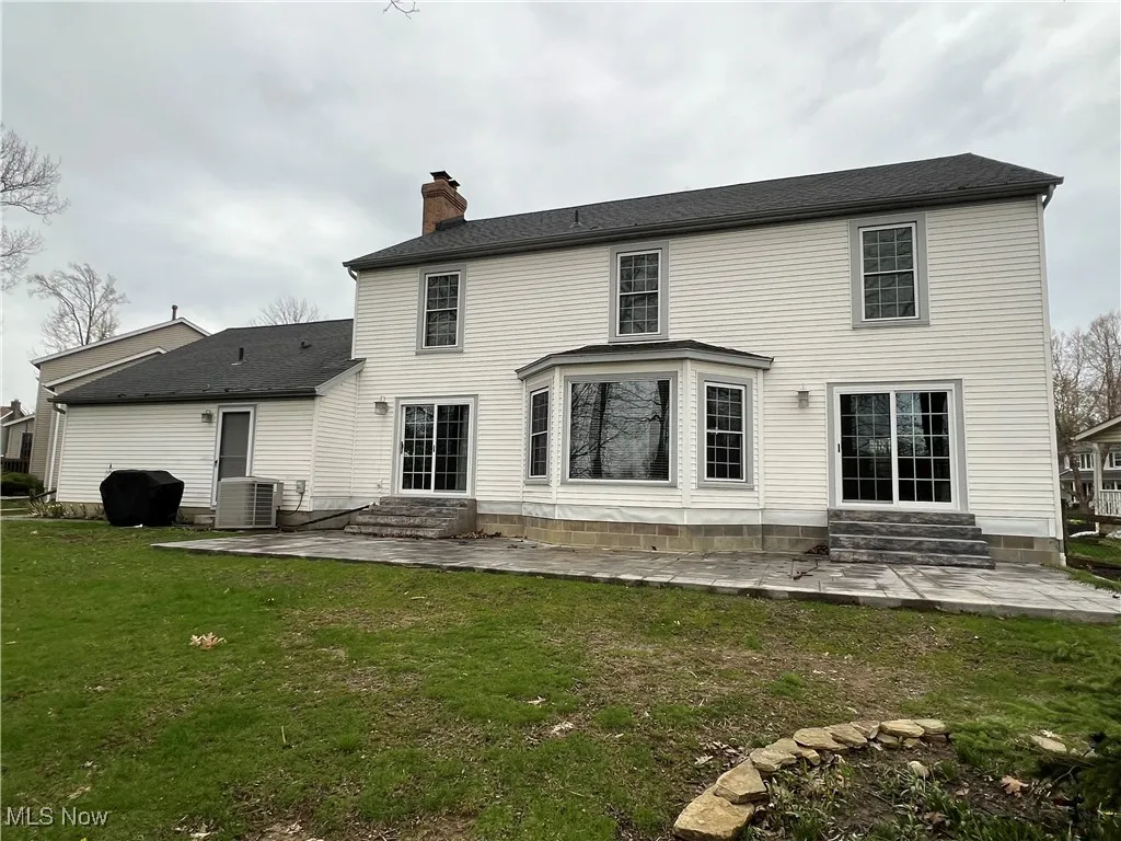 Back of house featuring central air condition unit, entry steps, a patio area, and a chimney