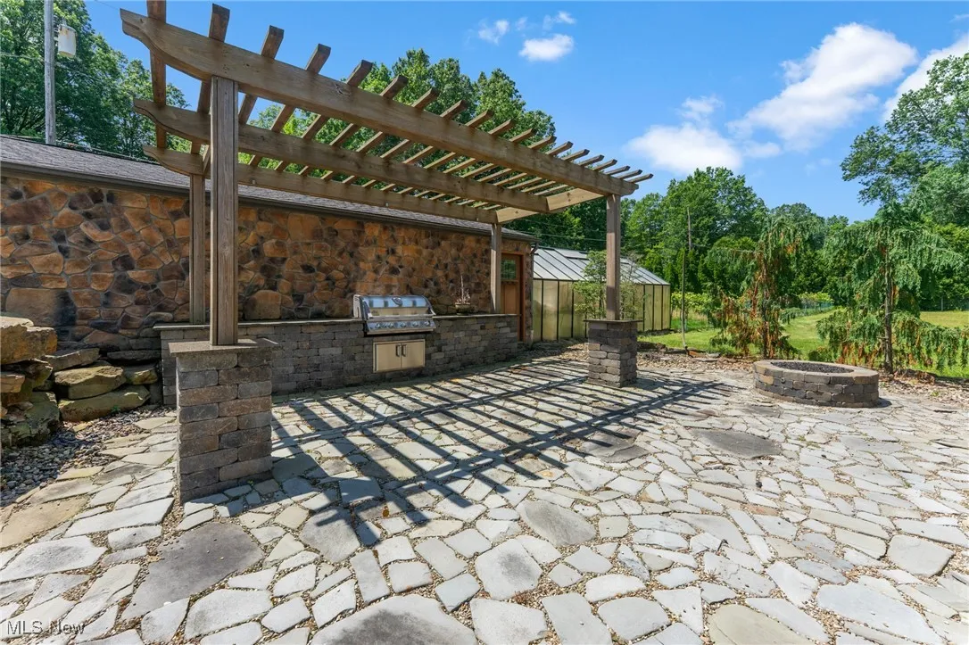 View of patio / terrace with an outdoor fire pit, an outdoor kitchen, and a pergola